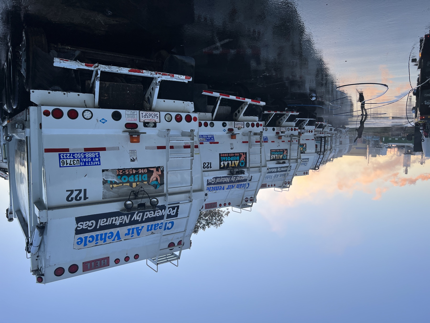Fleet of trucks being washed at sunrise