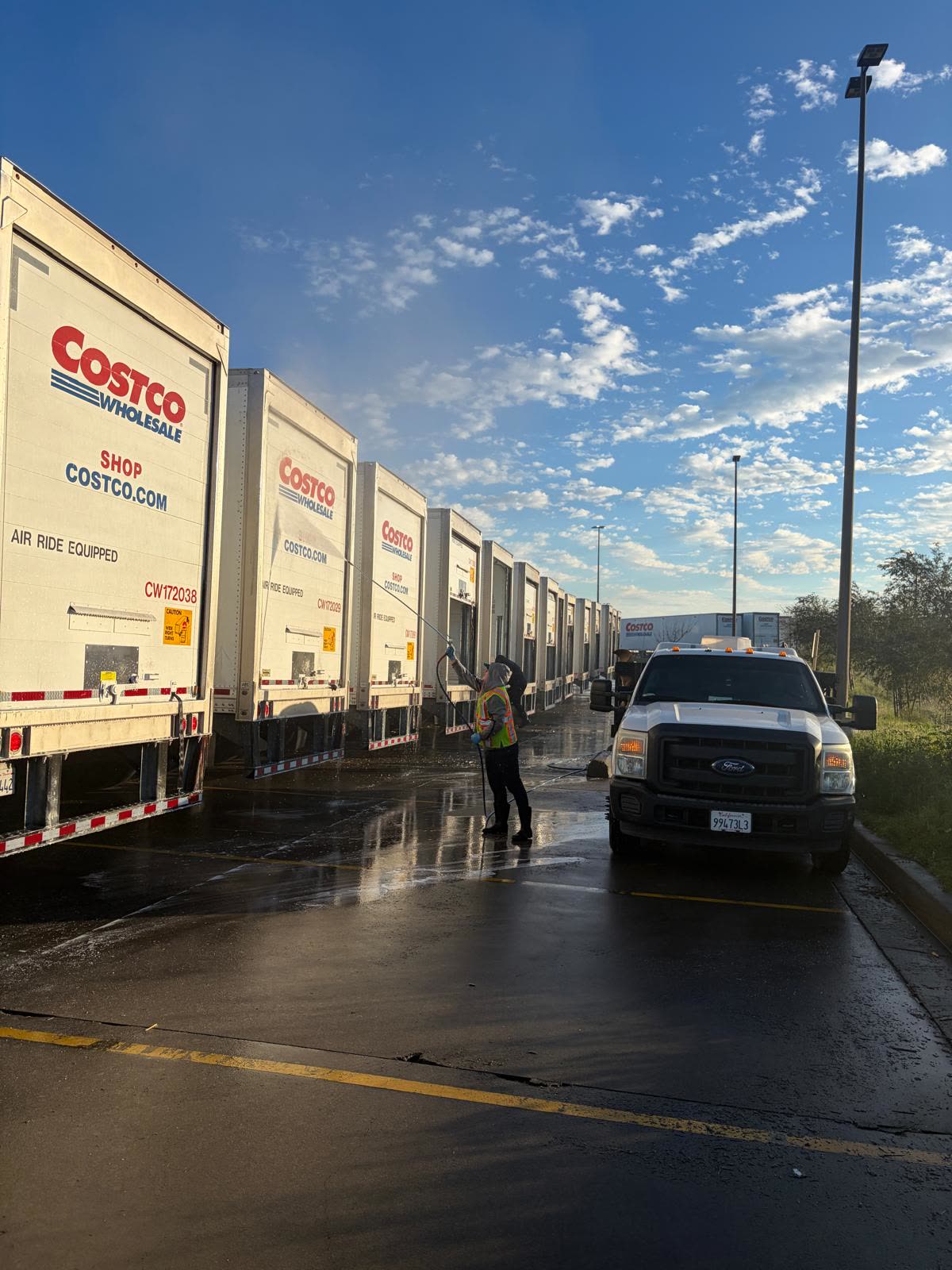 Crew washing a row of Costco trailers
